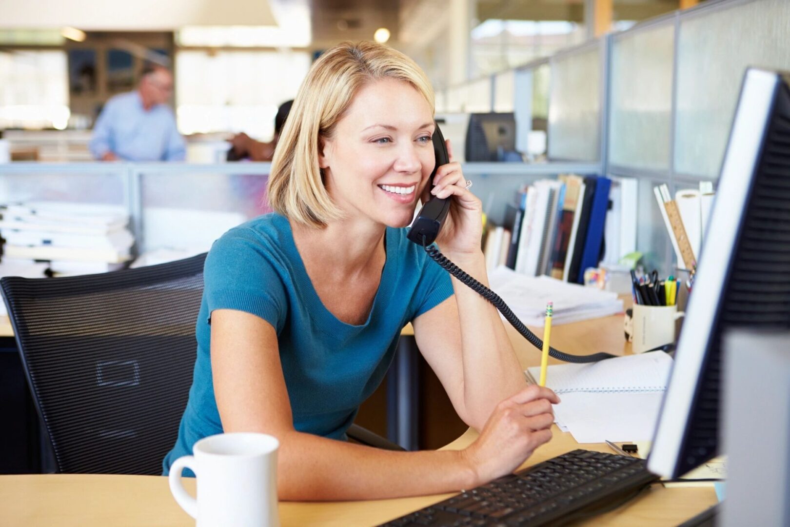 A woman sitting at her desk on the phone